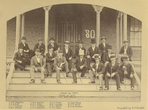 Members of Class of 1880 sitting outdoors, in front of building