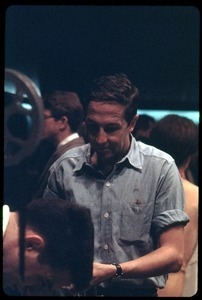 Artist Robert Rauschenberg, in front of a 16mm projector at a reception