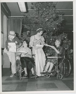 Performers giving gifts to two women in wheelchairs