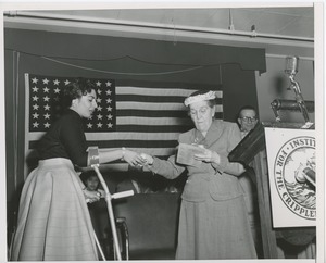 Unidentified woman handing gift to woman with forearm crutches at an ICD event