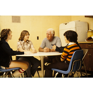 Five people speaking around a kitchen table