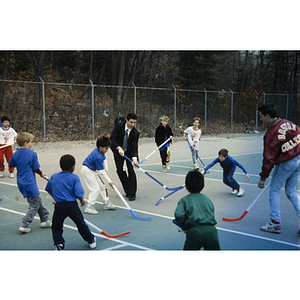 Field hockey game on an outdoor tennis court at the Eastern Middlesex Family YMCA