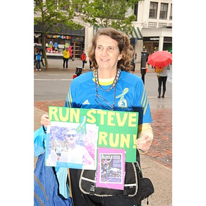 Woman holding poster stands on Boylston Street at One Run