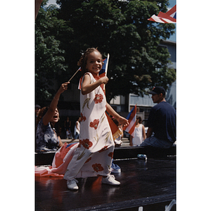 A young girl stands on a parade float waving a Puerto Rican flag at the Festival Puertorriqueño