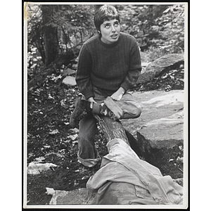 A female staff member sits on a trunk of a tree, looking upwards