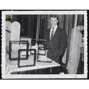 A Boys' Club member stands with frames and bookshelves at the Awards Night Exhibit