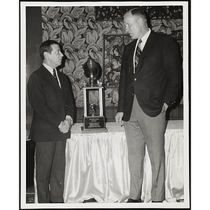 Bertram A. Druker, real estate developer (left) and John U. Harris, Jr., Overseer of the Boys' Clubs of Boston (right) talking in front "The Druker Award" trophy at the New England Pro Football Writers' second annual awards dinner at Hynes Memorial Auditorium