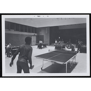 Two boys play table tennis in a hall