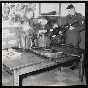 Two soldiers introduce three boys to army rifles