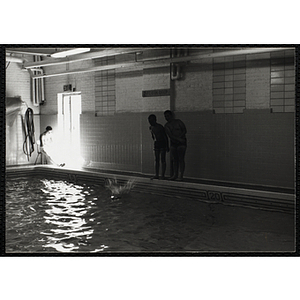 Two boys stand on the edge of a natorim pool