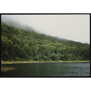 Fog lowers over a ridge above a pond