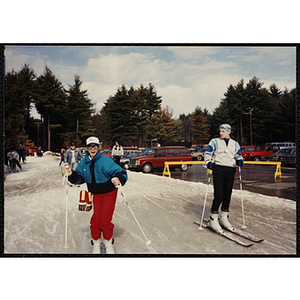 A boy stands on skis as a man looks on