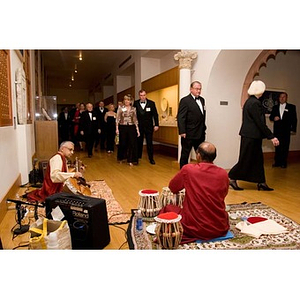 Guests file past two musicians on the floor at the Museum of Fine Arts