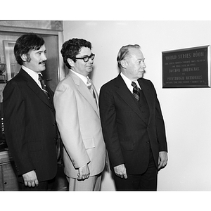 Three men look at a plaque at the dedication of the World Series Room in Cabot Physical Education Center