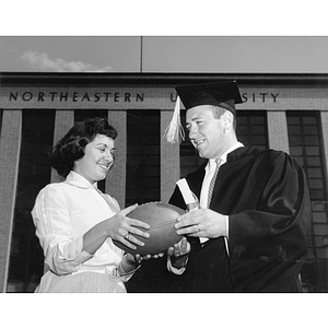 Marcia Halprin hands a football to her husband and graduate Harold A. Caplan at the 1960 commencement ceremony