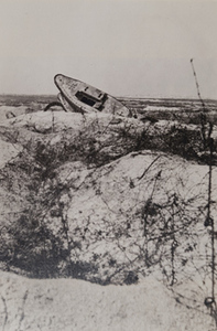 Overturned German tank and barbed wire in a war-torn field