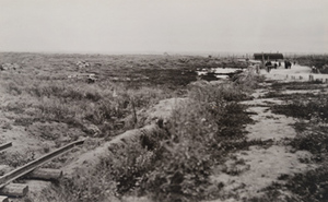 Damaged tanks visible lying in a field along a roadside and a narrow gauge railway, Menin Road, between Ypres and Menen
