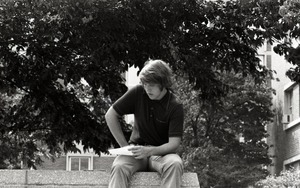 UMass Amherst students seated on a low wall, reading from a piece of paper