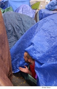 Occupy Wall Street: man reaching out of a tent, testing for rain