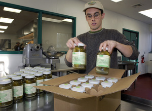 Young man packing jars of Real Pickles pickles for shipment