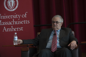Congressman Barney Frank holding a bottle of water while seated on the Student Union Ballroom stage, UMass Amherst, during his book event