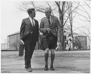 Hugh MacDiarmid, walking with a gentleman in front of Goodell while smoking