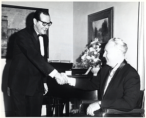 Mayor John F. Collins wearing medal and shaking hands with unidentified man