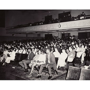A photograph of the audience seated in an auditorium
