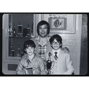 A man posing with two boys holding their trophies at a Boys' Clubs of Boston Awards Night