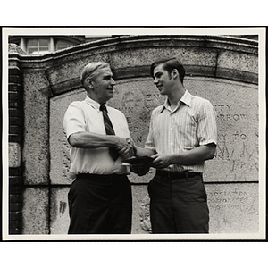 A Boys' Club staffer shakes hands with a young man as he presents an award in front of the memorial stone outside the Charlestown Clubhouse