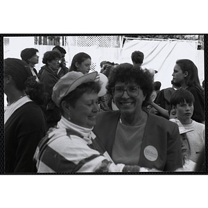 A woman wearing glasses smiles for the camera while standing with a staff member wearing a hat at the Boys and Girls Clubs of Boston 100th Anniversary Celebration Street Fair