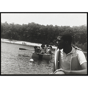 Four youth and a supervisor sit in a rowboat behind an adult in a life vest