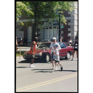 A boy and a man run by spectators during the Battle of Bunker Hill Road Race