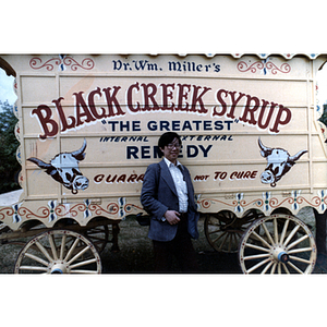 Chinese Progressive Association member poses in front of an old-fashioned merchant's cart during a trip to Toronto