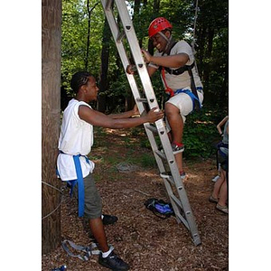 Michael Toney holds a ladder for Ulysses Ifill at the Torch Scholars Project Adventure Ropes Course