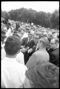 News media interviewing David Dellinger (back to camera) and Staughton Lund (back to camera, far left) during peace march in Washington