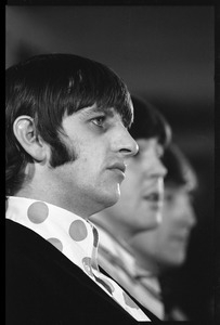 Ringo Starr during a Beatles press conference: in profile: Paul McCartney partly visible in the background