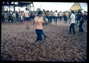 Woman carrying drinking cups through a muddy field, Woodstock Festival
