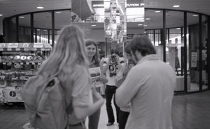 Commune member distributing Free Spirit Press in an indoor shopping mall: self-portrait of photographer photographing a group talking about the magazine