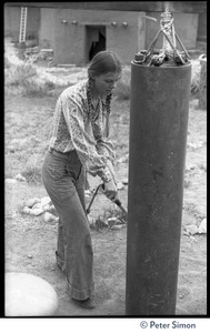 Young woman ringing a cylindrical gong, Lama Foundation