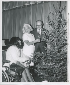 Margaret Milbank Bogert and Dr. DiMichael decorating Christmas tree with client in wheelchair