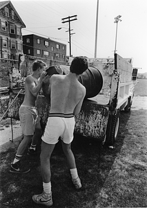 Two men loading a barrel into a truck