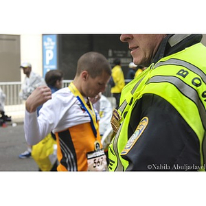 Boston Police Officer standing by runners who have just completed the 2013 Boston Marathon