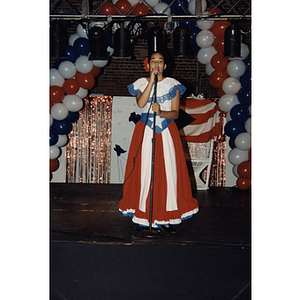 A girl in a Puerto Rican flag dress sings into a microphone at the Festival Puertorriqueño