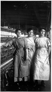 Three female textile workers at a spinning frame.