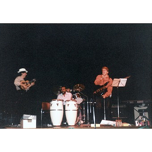 Claudio Ragazzi, Alex Alvear, and an unidentified drummer perform on stage for their colleagues.