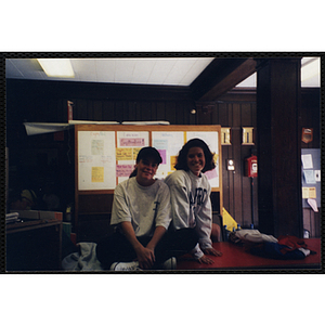 Two young women sitting on a table and smiling for the camera during a Boys & Girls Club event