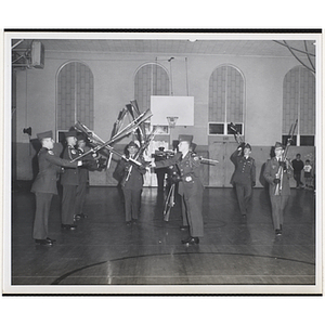 The Boston University drill team perform a rifle maneuver in a gymnasium