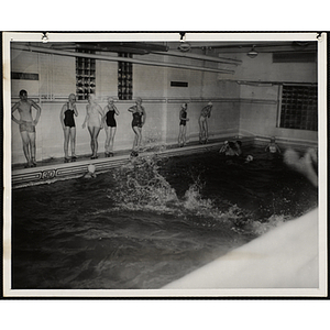 Teenagers stand by and swim in a natatorium pool