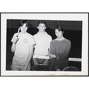 Three teenage boys with tennis racquets stand by the nets at the South Boston gymnasium